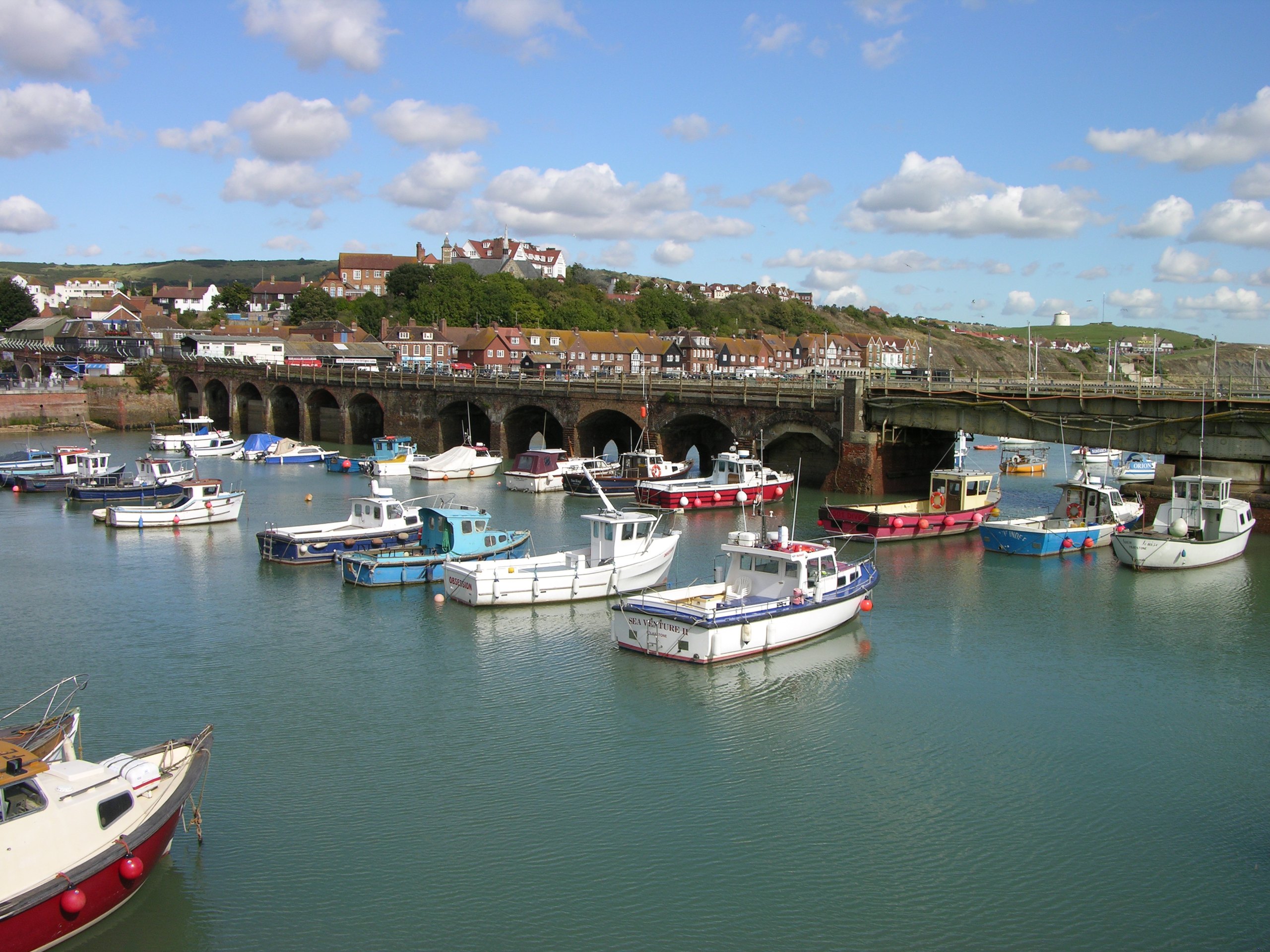 Boats in Folkestone Harbour beneath the railway viaduct under a blue sky