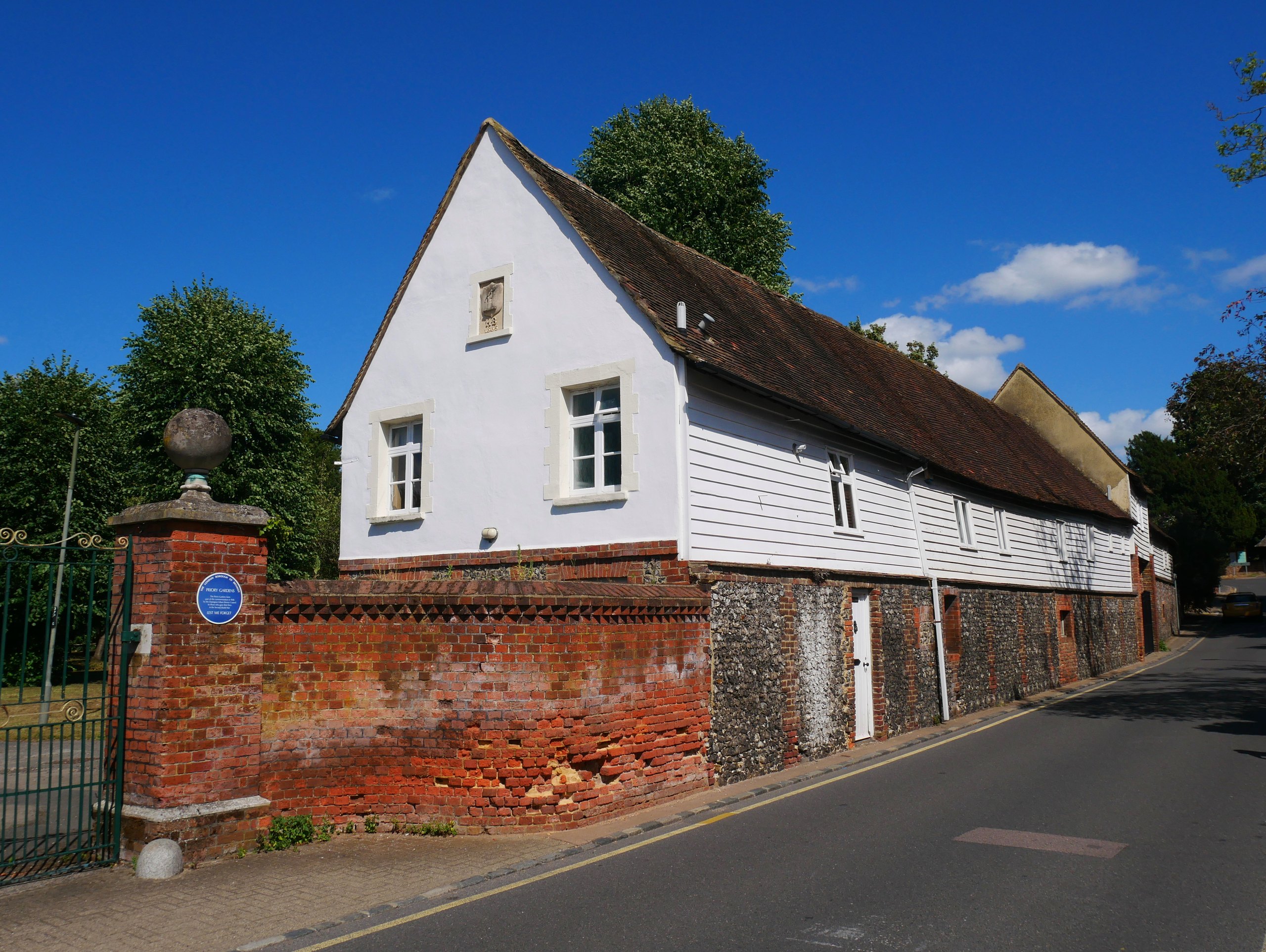 The white weatherboarded Priory outbuildings in Orpington under a blue sky
