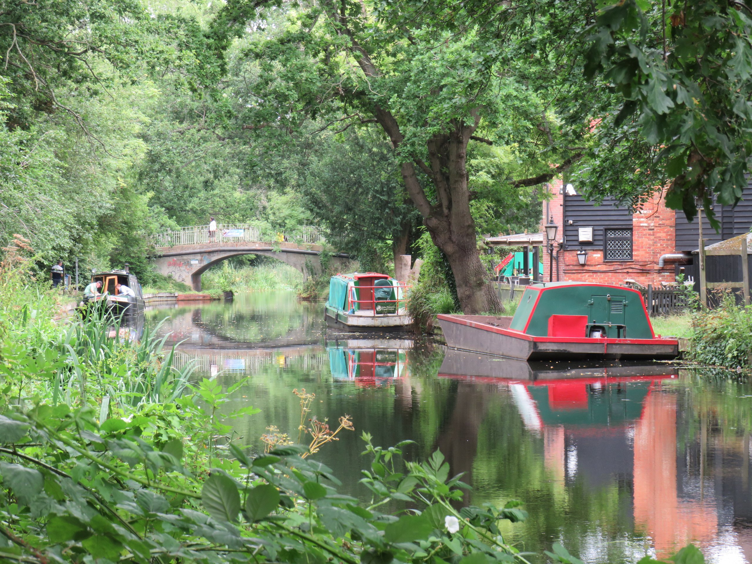 Narrowboats and a brick bridge on the Basingstoke Canal at Woking