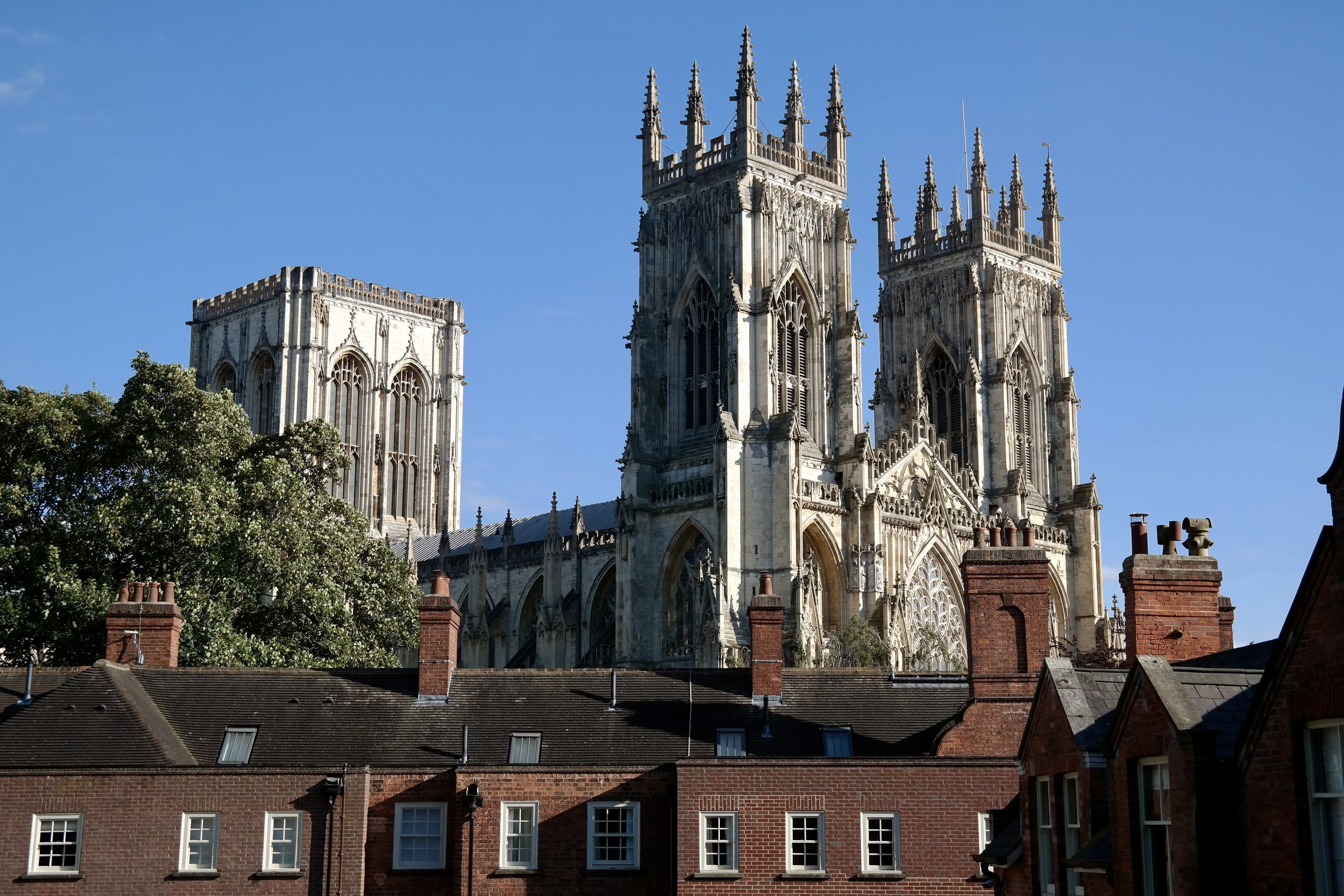 The twin towers of York Minster above the rooftops against a blue sky